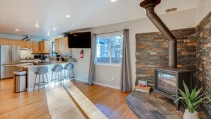 A modern kitchen with a central island, bar stools, and a stone fireplace. - Ski & Board in South Lake Tahoe! Updated Home (South Lake Tahoe)