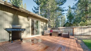A wooden deck with a grill and outdoor furniture, surrounded by a wooden fence and trees. - Ski & Board in South Lake Tahoe! Updated Home (South Lake Tahoe)