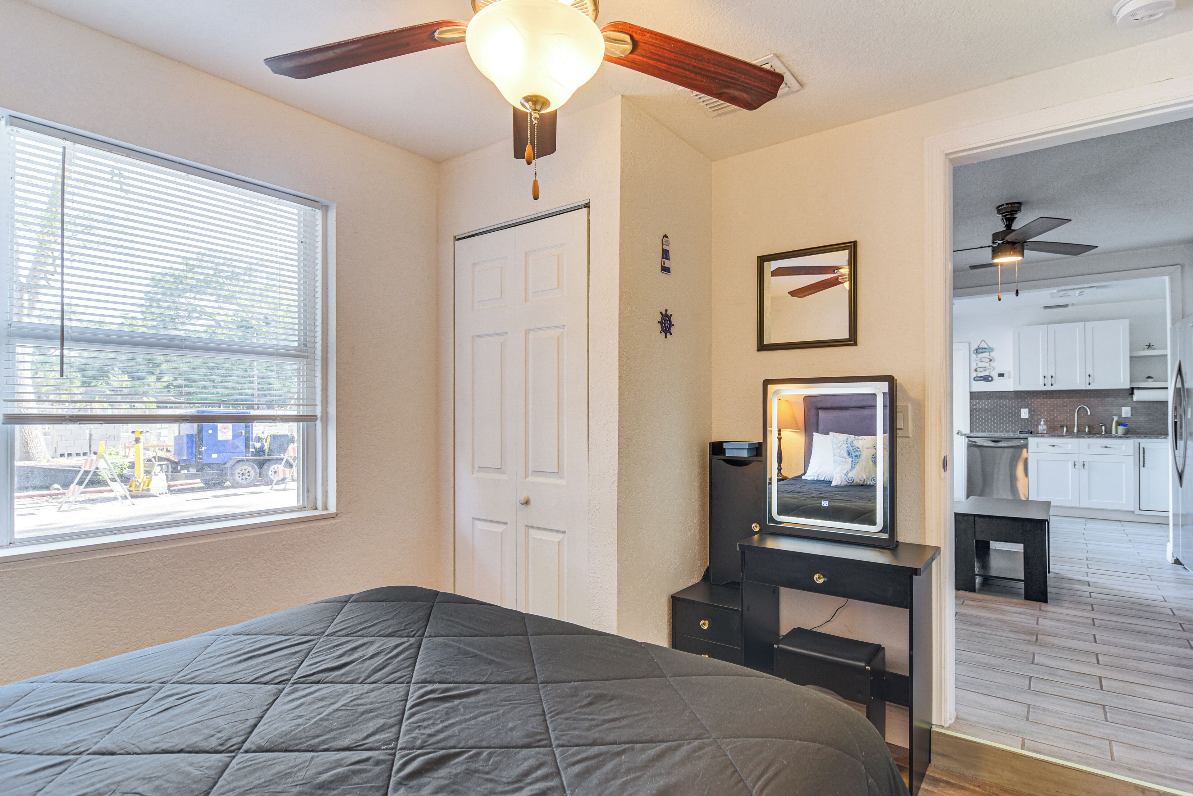 A bedroom with a bed, a dresser, a mirror, and a ceiling fan.