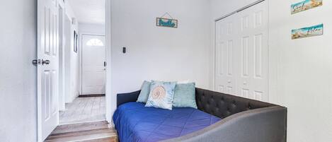 A bedroom with a bed, a headboard, a door, and a hallway.