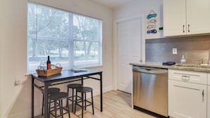 A kitchen with a dining area, a dishwasher, and a window with blinds. - Walk to Art District + Beach: Pet-friendly Getaway (St. Petersburg)