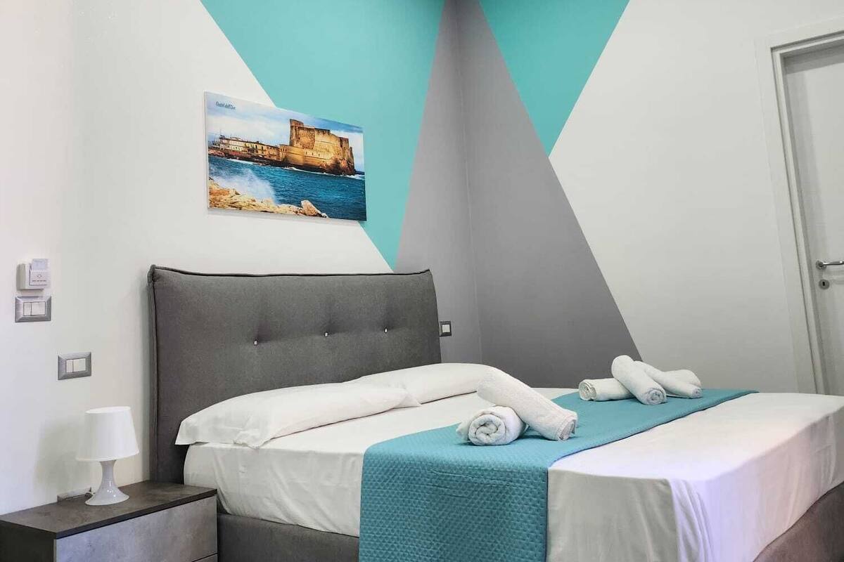 Un dormitorio moderno con cama, mesita de noche y una pintura de una escena costera.