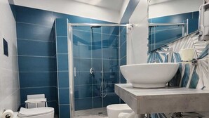 A modern bathroom with a glass-enclosed shower, a white toilet, and a vanity with a bowl sink and towels. - GRADINI PARTENOPEI (Naples)