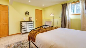A bedroom with a bed, a dresser, a door, a lamp, and a window with curtains. - Redmond Vacation Rental ~ 16 Mi to Seattle! (Redmond)