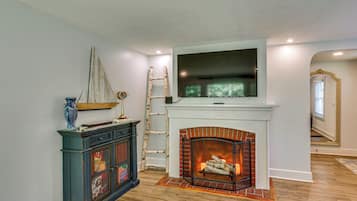 Una sala de estar con chimenea, un televisor montado encima y un mueble decorativo con un velero en la parte superior.