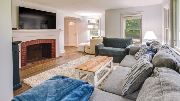 A living room with a fireplace, a sofa, a coffee table, and a TV mounted above the fireplace. - Near Beach: Coastal Maine Getaway w/ Yard (Wells)