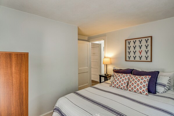 A bedroom with a bed, a nightstand, a lamp, and a framed picture on the wall.
