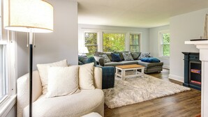 A cozy living room with a plush sofa, a coffee table, and a fireplace. - Near Beach: Coastal Maine Getaway w/ Yard (Wells)