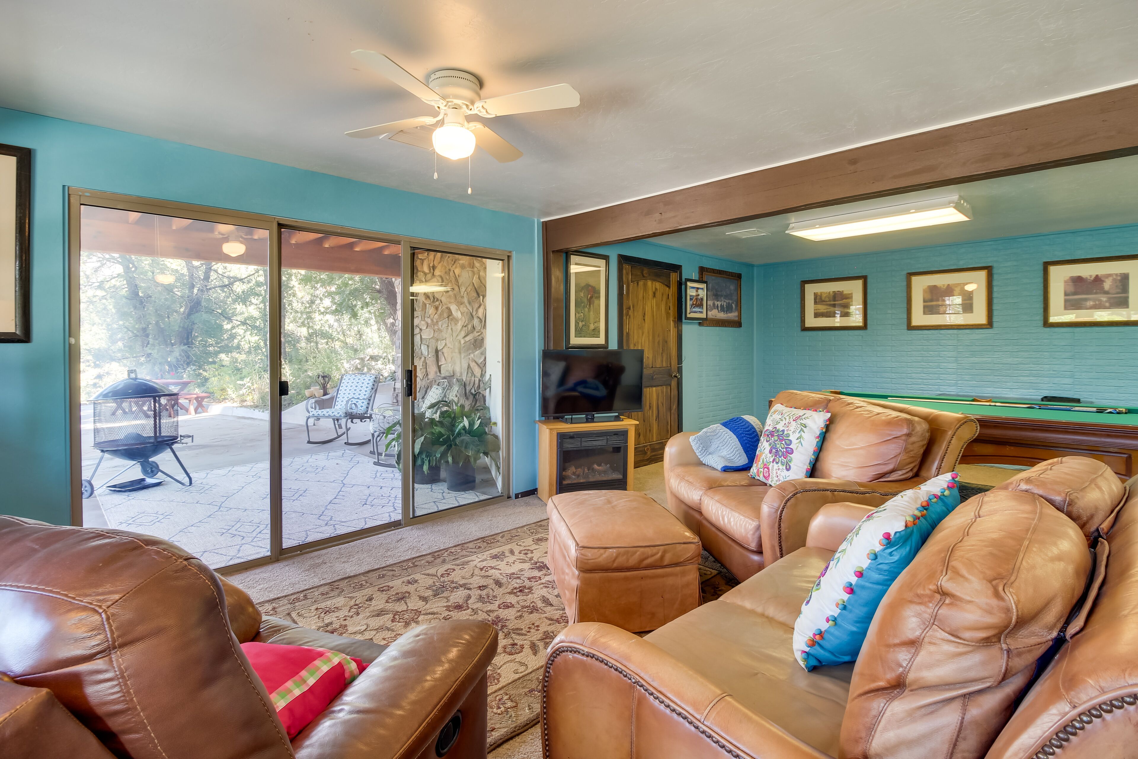 A living room with leather sofas, a pool table, and a television.