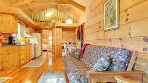 Ein Blockhaus-Interieur mit Holzwänden, einer Couch, einem Essbereich und einer Küche.