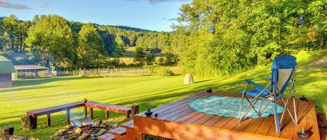 Eine Holzterrasse mit Whirlpool, Picknicktischen und Feuerstelle.