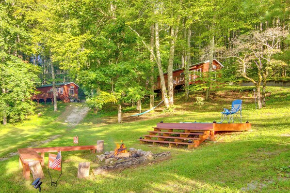 Una cabaña con un hogar y una mesa de picnic en un área boscosa.