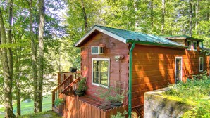 A rustic cabin with a wooden deck, surrounded by lush greenery and trees. - Hendersonville Cabin Near Hiking & Waterfalls! (Hendersonville)