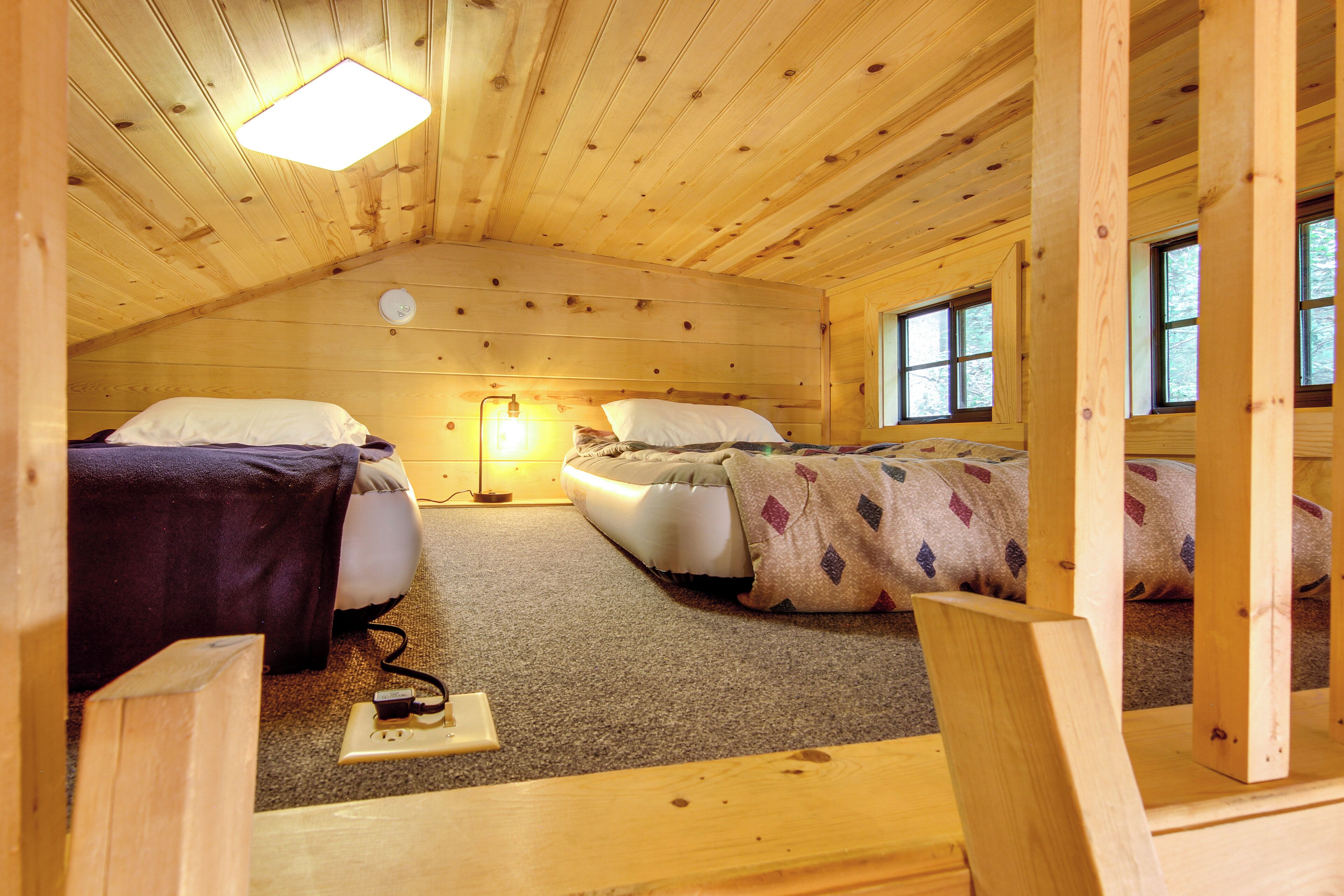 A cabin with two beds, a ceiling light, and windows.