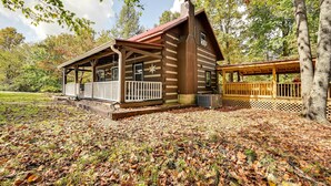 A rustic cabin with a porch, a chimney, and a deck.