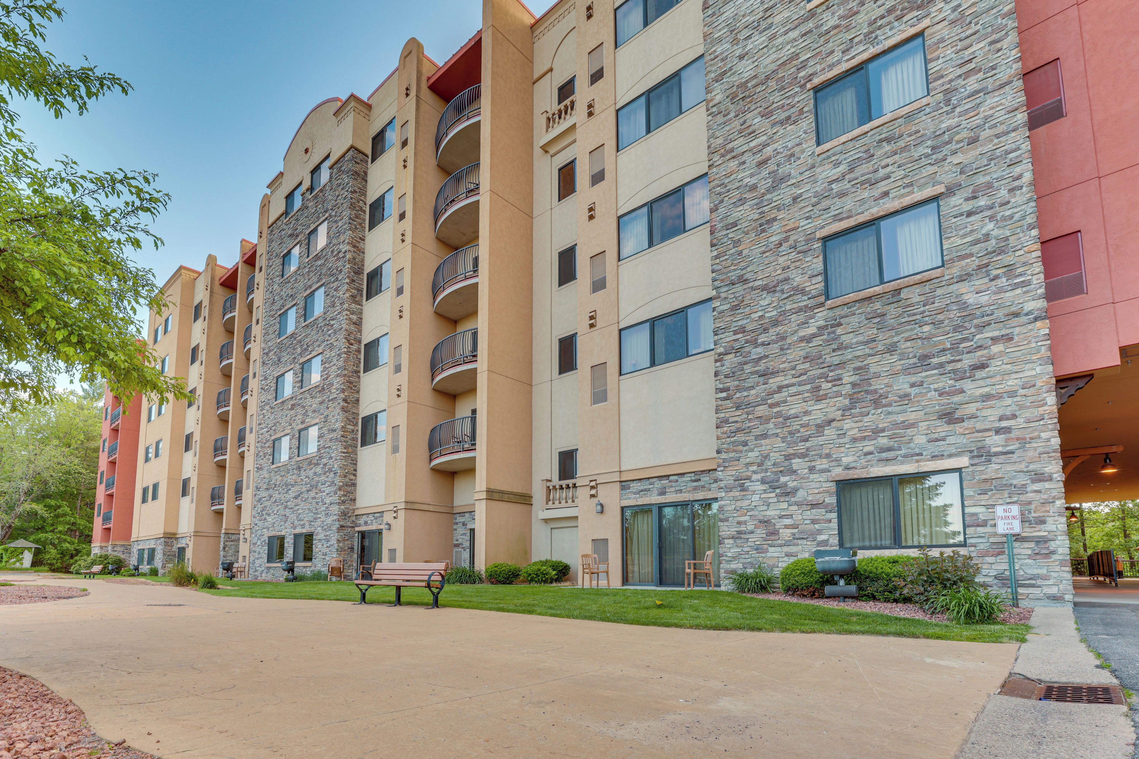 A multi-story building with balconies, a patio area with a bench, and a 'No Parking' sign.