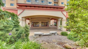 A hotel entrance with a covered walkway, stone steps, and a landscaped garden with shrubs and a small stream. - Wisconsin Dells Resort Condo w/ 2 Fireplaces (Wisconsin Dells)