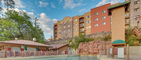 A hotel with a swimming pool, multiple balconies, and a view of the surrounding landscape.