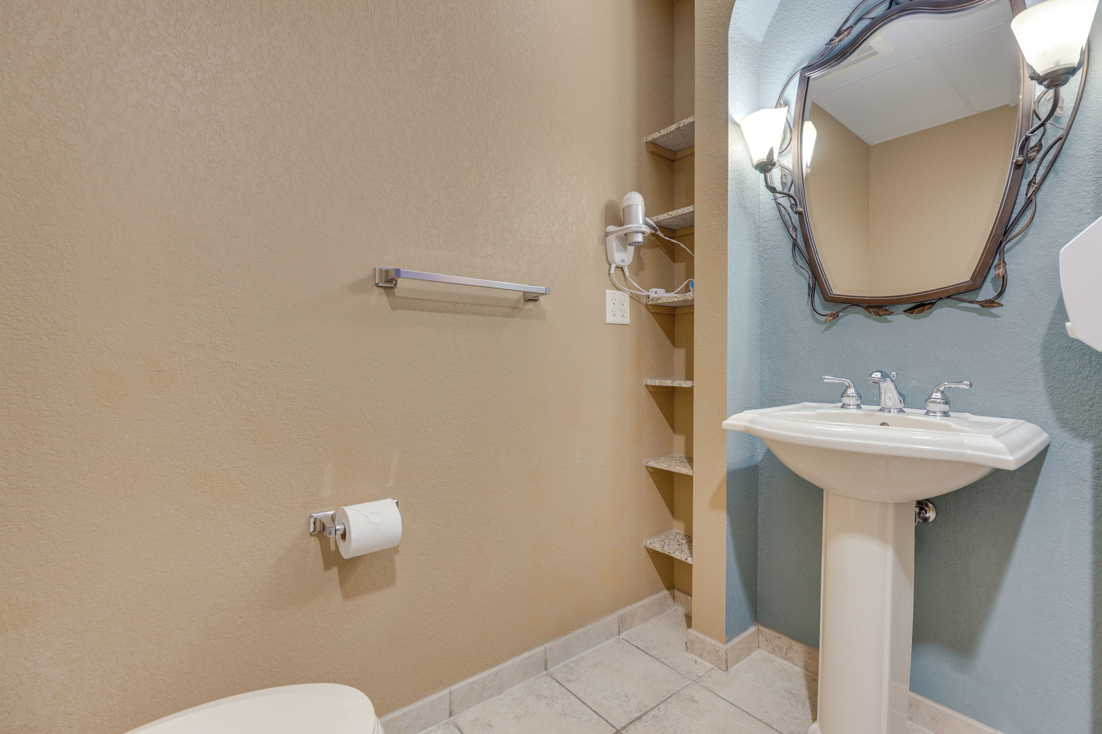 A bathroom with a toilet, a sink, a mirror, and a towel rack.