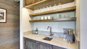 Een keuken met houten kastjes, een marmeren werkblad, een spoelbak en planken met glaswerk.