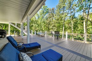 A covered deck with outdoor furniture, a grill, and a staircase leading to a higher level. - Lakefront Gilbertville Haven w/ Private Boat Dock! (Gilbertsville)