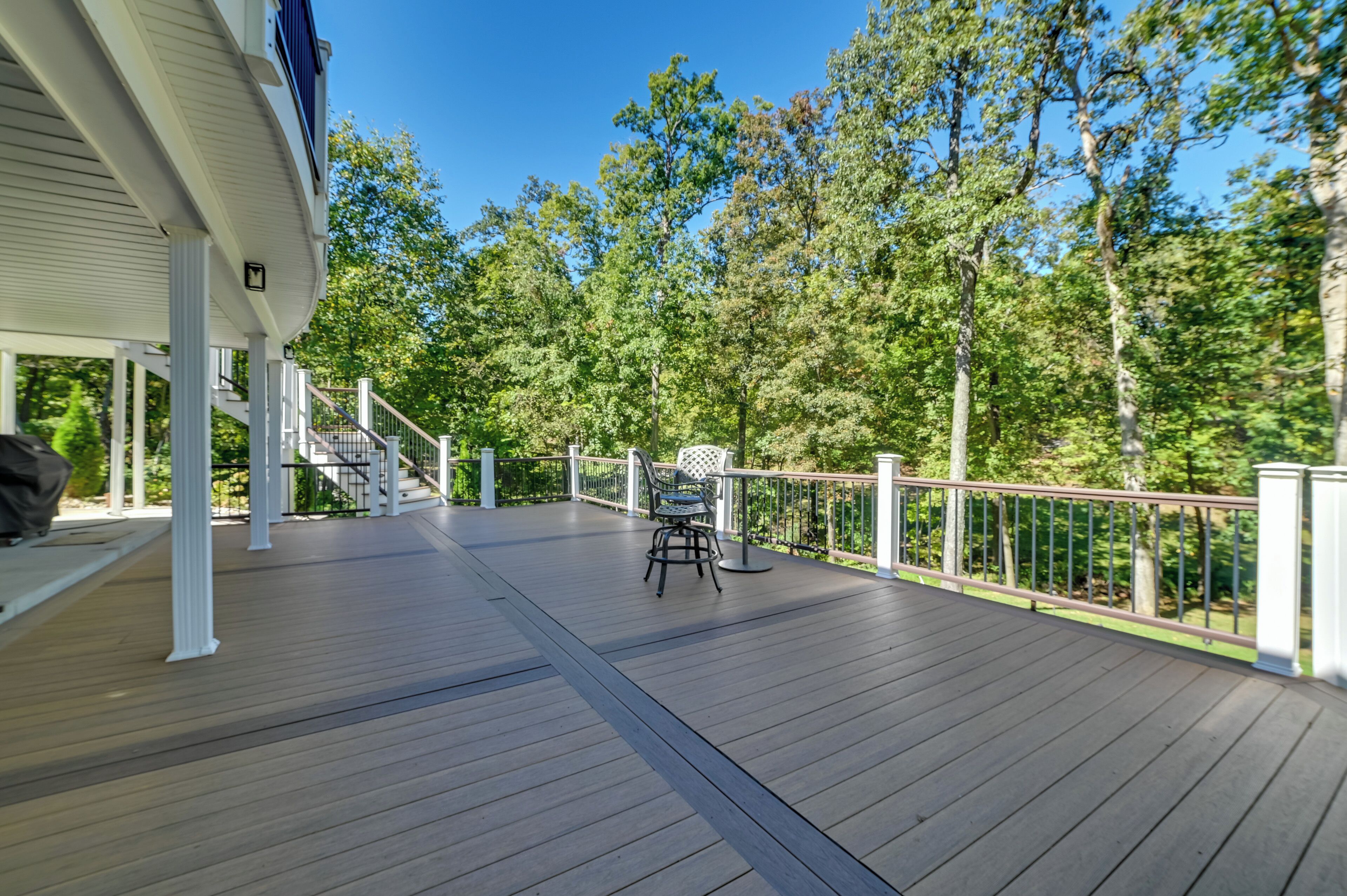 A wooden deck with a chair and a staircase leading to a covered area.