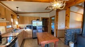 A modern kitchen with wooden cabinets, stainless steel appliances, a central island, and a stone fireplace.