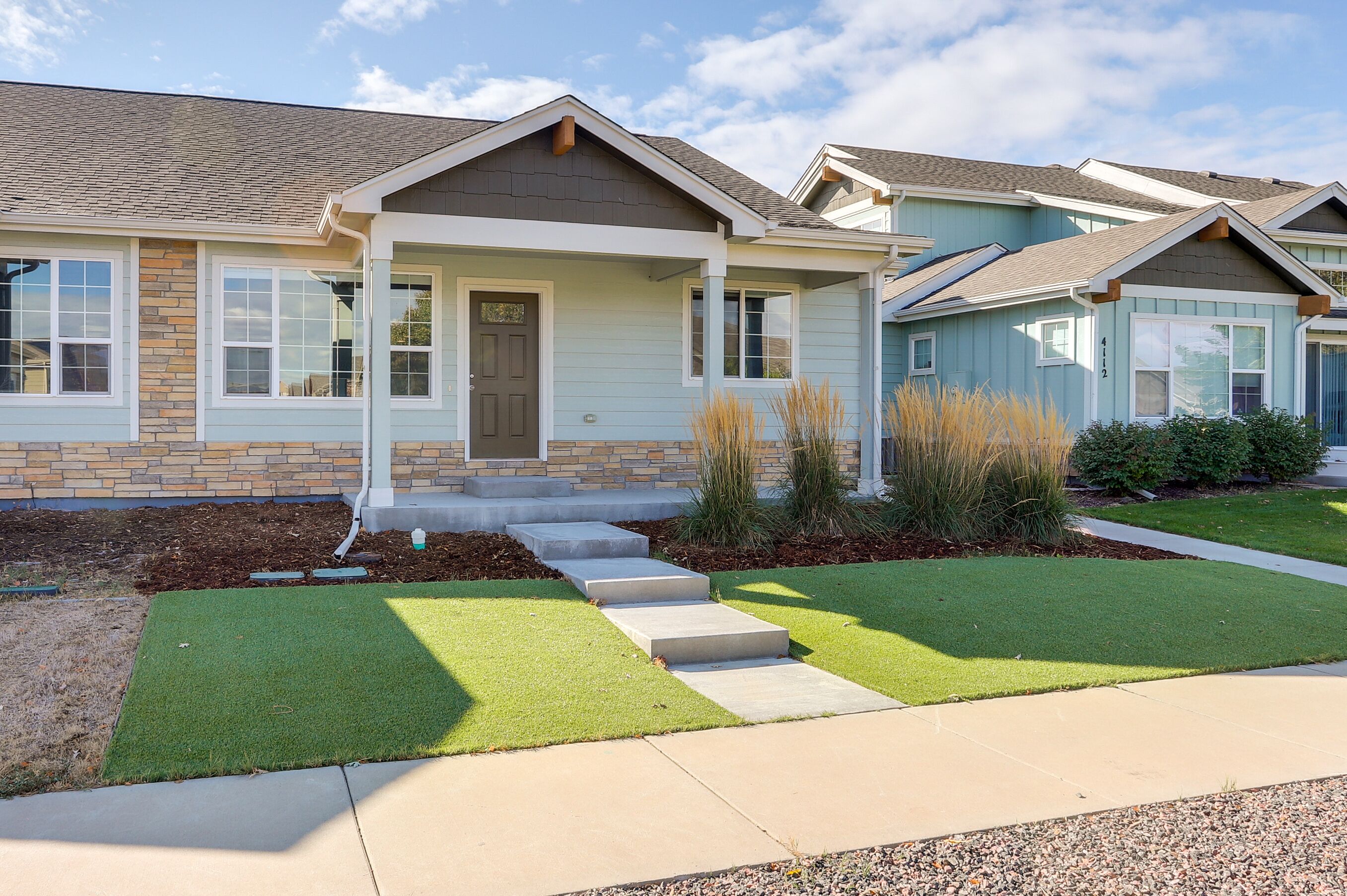 A residential building with a front porch, a door, and a small set of steps leading to the entrance.