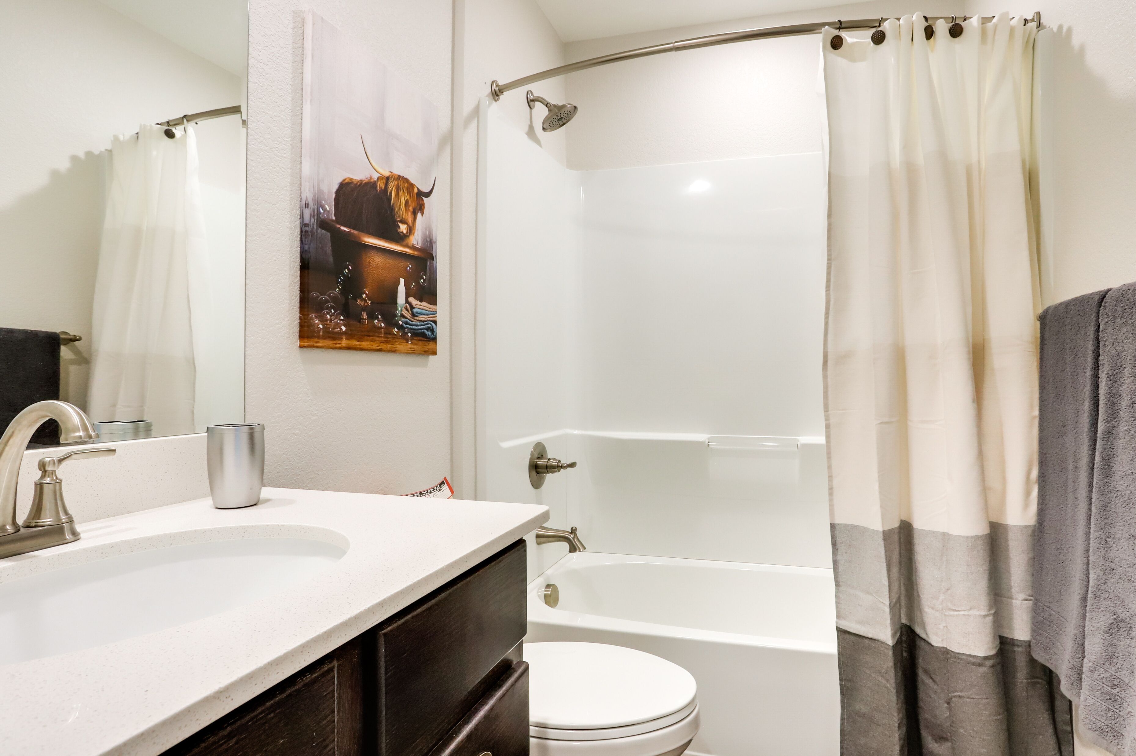 Une salle de bain avec un lavabo blanc, des toilettes, une baignoire et un rideau de douche.
