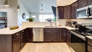 A modern kitchen with dark wooden cabinets, stainless steel appliances, and a white countertop. - Quiet Evans Home Rental Near Parks & Downtown! (Evans)
