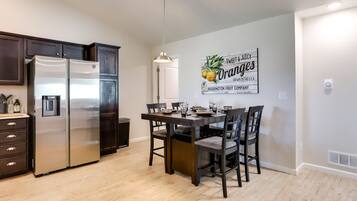 A modern kitchen with dark wooden cabinets, stainless steel appliances, and a dining area with a wooden table and chairs.