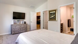 A bedroom with a large bed, a dresser, a flat-screen TV, and a closet with a door leading to another room. - Quiet Evans Home Rental Near Parks & Downtown! (Evans)
