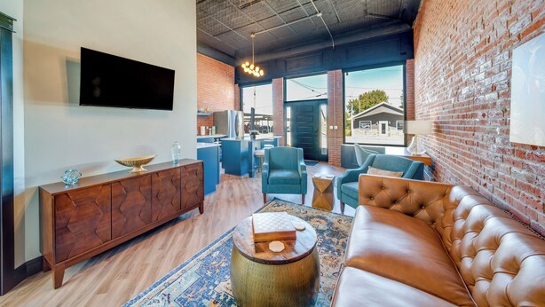 Een moderne woonkamer met een leren bank, een houten salontafel en een blauwe fauteuil.