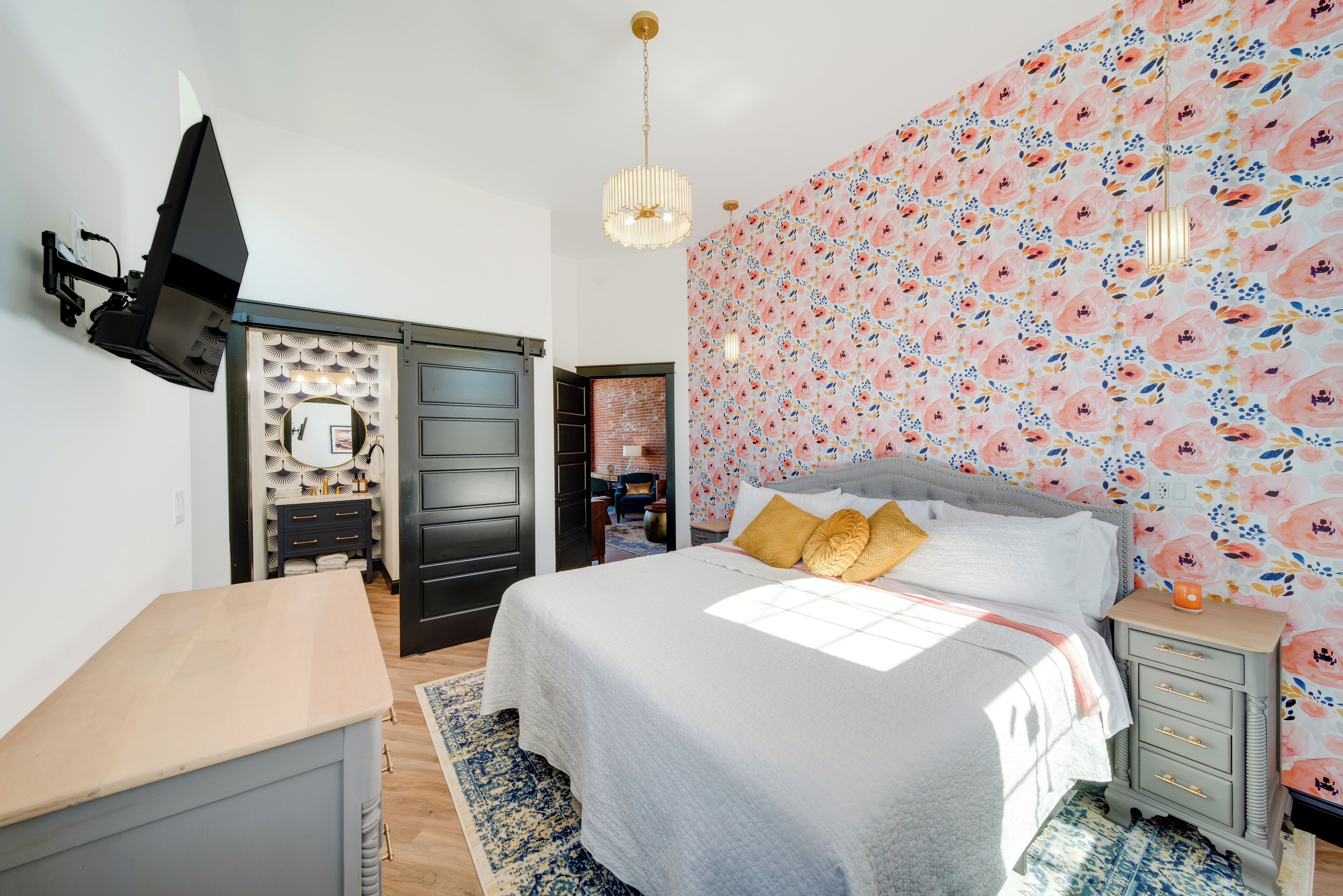 A bedroom with a bed, a dresser, a vanity, and a mirror.