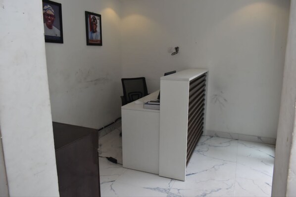 Un pequeño espacio de oficina con un escritorio blanco, una silla y un radiador. Hay dos cuadros en la pared.