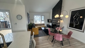 A modern kitchen with a dining area, a sofa, and a fireplace. - Location! New, Modern Townhouse Steps from 124 Street! (Edmonton)