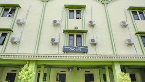 A building with a sign reading "OYO LIFE" and multiple air conditioning units attached to the exterior walls.
