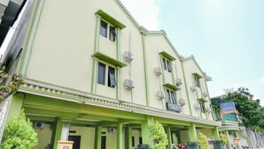 A multi-story building with green accents and multiple air conditioning units.