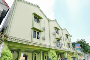 Un edificio de varios pisos con detalles en verde y múltiples unidades de aire acondicionado.
