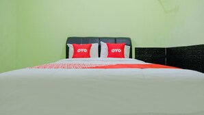 A bed with a white and red bedspread, two red pillows with "OYO" text, and a dark headboard.