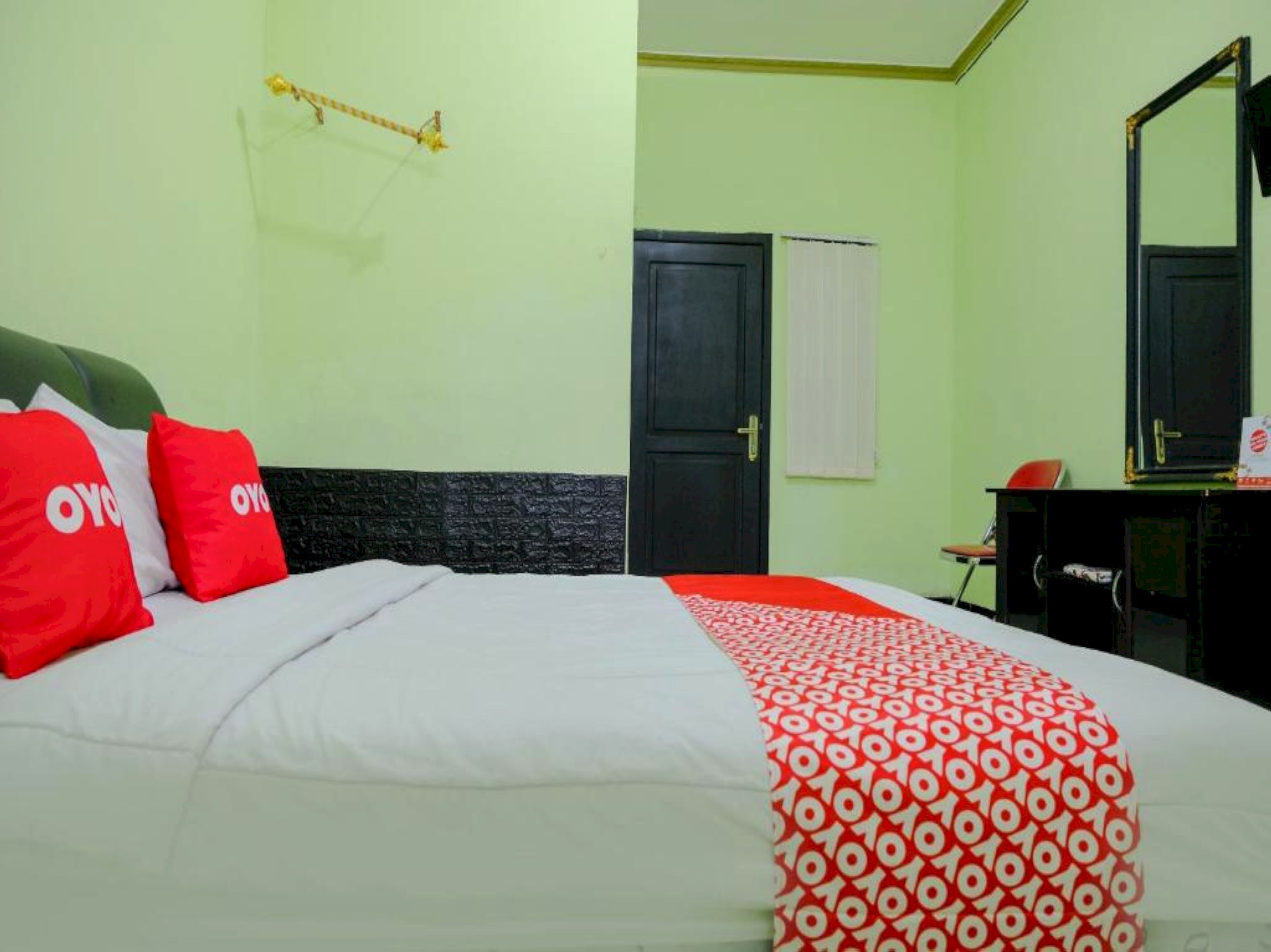 Une chambre d’hôtel comprenant un lit, un bureau, une chaise, une armoire et un miroir.