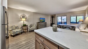 A modern kitchen with a marble countertop, a built-in oven, and a dining area with a bench and table.