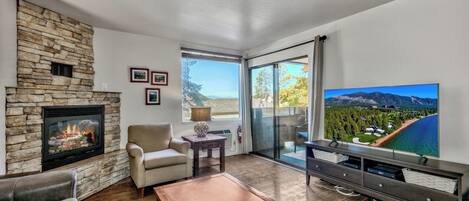 A living room with a stone fireplace, a television, and a large window with a scenic view.