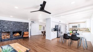 A modern living room with a fireplace, dining area, and kitchen. - Beautiful, Sunshine Paradise Escape! (Phoenix)