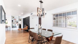 A modern dining area with a glass table, brown chairs, and a stone accent wall. - Beautiful, Sunshine Paradise Escape! (Phoenix)