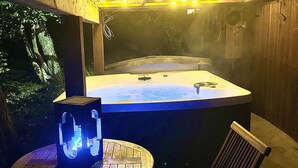A hot tub with a table and chairs in a covered outdoor area.