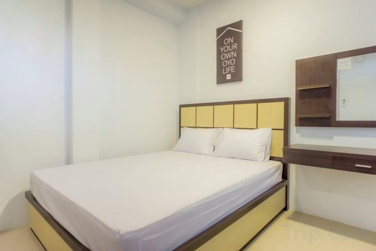 A single bed with a wooden headboard, a bedside table, and a mirror.