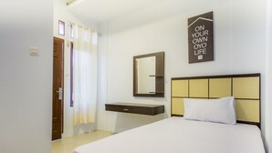 Une chambre d’hôtel avec un lit, une table de chevet, un miroir et un panneau fixé au mur.