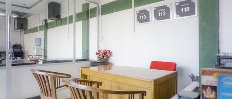 A conference room with a wooden table and chairs, a vase with flowers, and numbered signs on the wall.