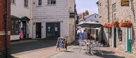 A street with a cafe named 'Oscar's Bistro' and a shop called 'Peach & Rogue.' There is a chalkboard sign in front of the cafe.